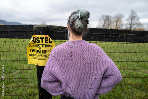 A woman in a big sweather looks across a fence near the Gunks in upstate New York, Catskills region photo