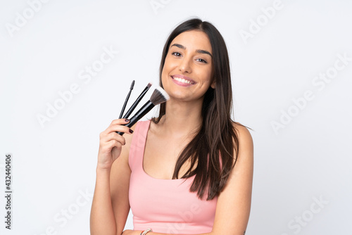 Young caucasian woman isolated on white background holding makeup brush