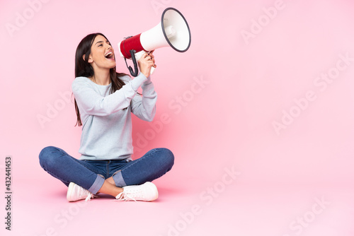 Fotótapéta Young caucasian woman isolated on pink background shouting through a megaphone