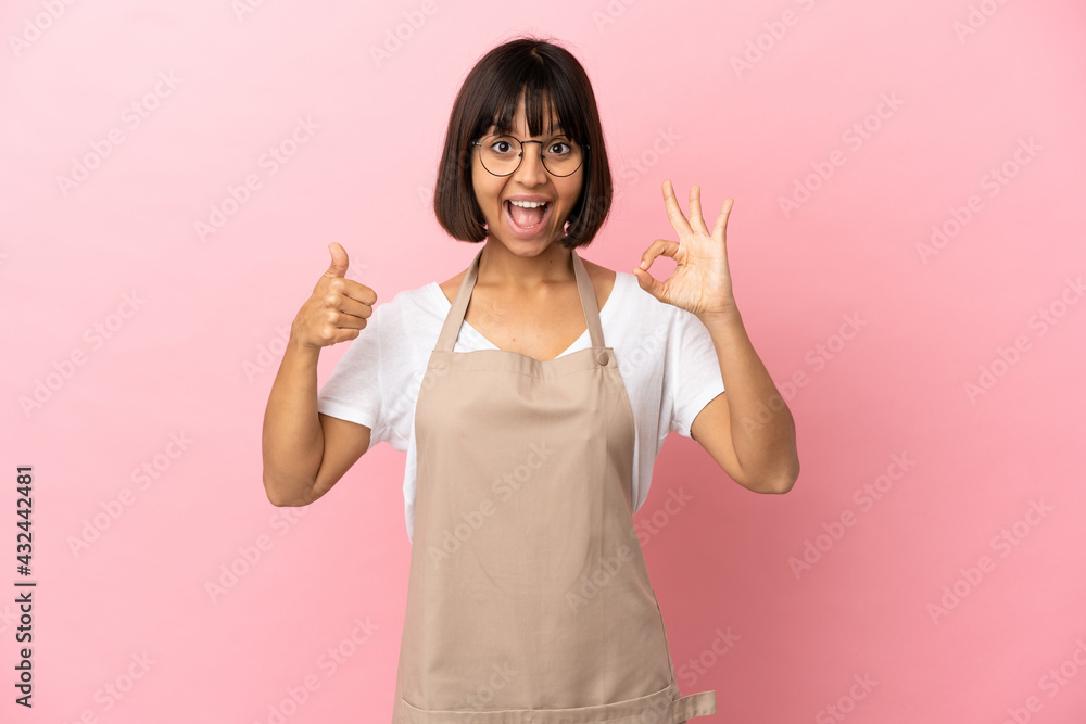 Restaurant waiter over isolated pink background showing ok sign and thumb up gesture Restaurant waiter over isolated pink background showing ok sign and thumb up gesture
