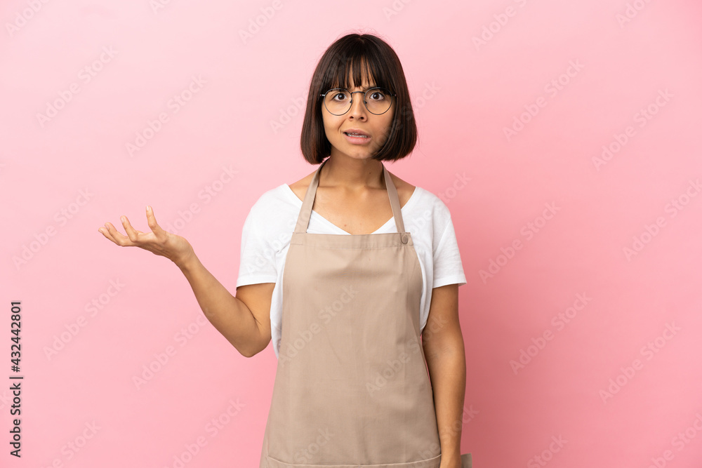 Restaurant waiter over isolated pink background making doubts gesture Restaurant waiter over isolated pink background making doubts gesture