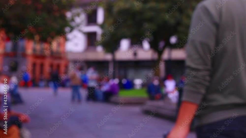 Blurred, unrecognisable people walking around in a city with other people wearing face masks sitting alongside perches, typical city life background of South America Blurred, unrecognisable people walking around in a city with other people wearing face masks sitting alongside perches, typical city life background of South America