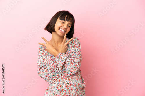 Young pregnant woman over isolated pink background smiling and showing victory sign