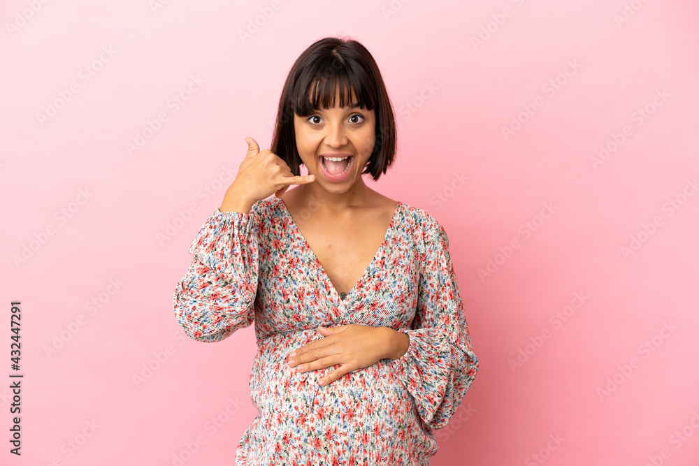 Young pregnant woman over isolated pink background making phone gesture. Call me back sign Young pregnant woman over isolated pink background making phone gesture. Call me back sign