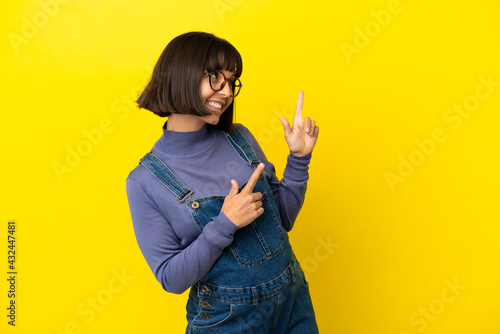 Young pregnant woman over isolated yellow background pointing with the index finger a great idea