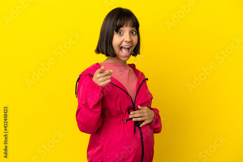 Young pregnant woman over isolated yellow background surprised and pointing front © luismolinero
