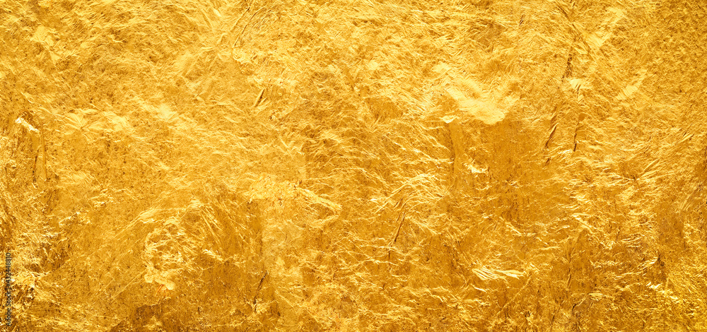 Fototapeta premium Shiny gold background made of rough textured gold leaf.