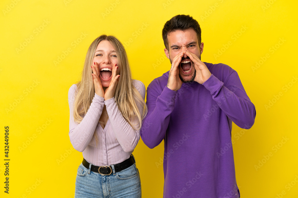 Young couple over isolated yellow background shouting with mouth wide open Young couple over isolated yellow background shouting with mouth wide open
