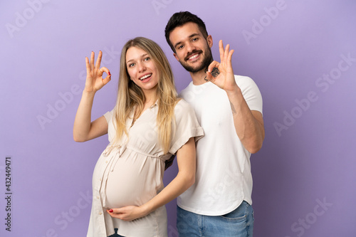 Young couple pregnant and doing OK sign