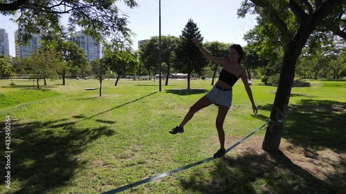 Young happy woman trying to balance on slack line at the park photo