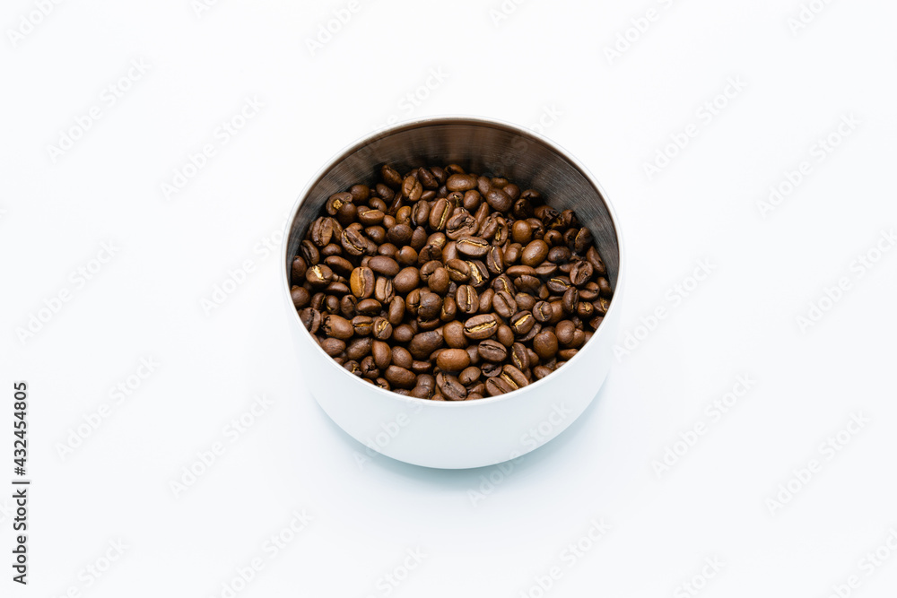 Mixture of different kinds of roasted coffee beans in white container on white background. Copy space.