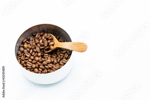 Mixture of different kinds of roasted coffee beans with wooden spoon in white container on white background. Copy space.