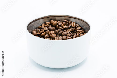 Mixture of different kinds of roasted coffee beans in white container on white background. Copy space.