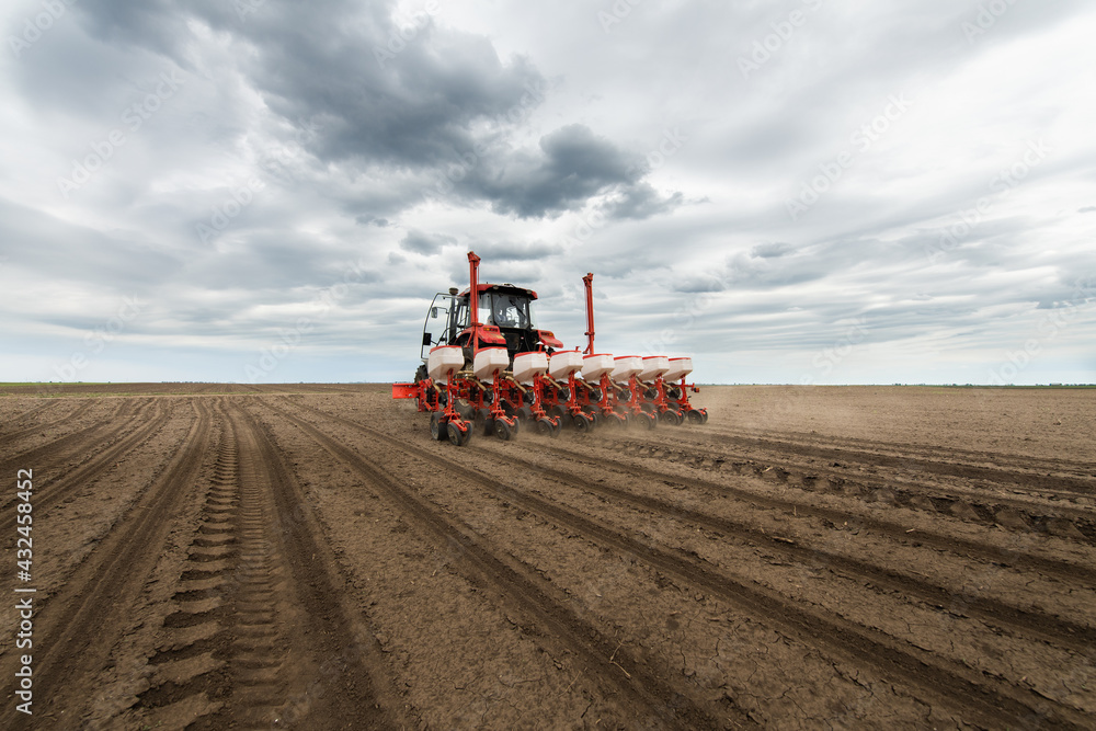 Farmer with tractor seeding crops at field Farmer with tractor seeding crops at field