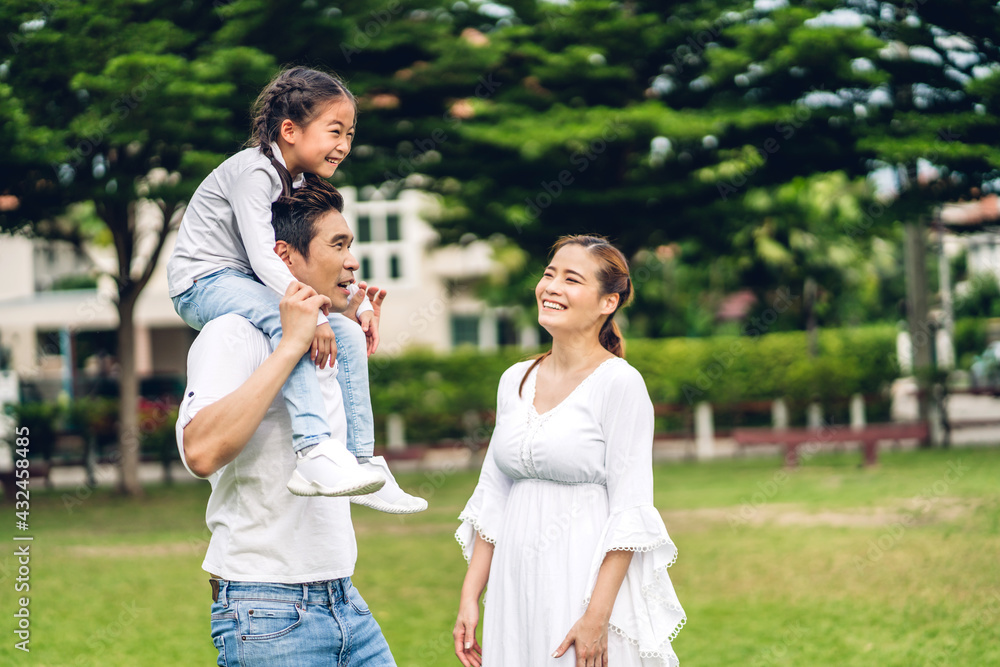 Fototapeta premium Portrait of enjoy happy love asian family father and mother holding cute little asian girl child smiling playing and having fun moments good time in summer park at home