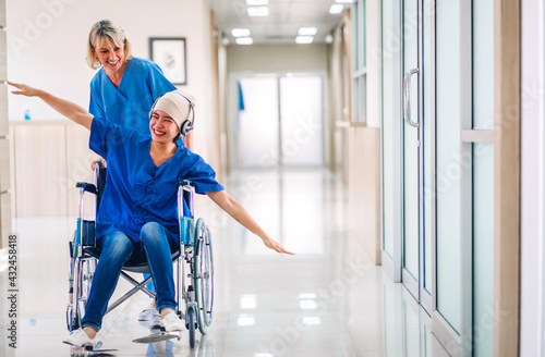 Fotografi Professional medical doctor with stethoscope in uniform discussing and dancing with happy patient woman with cancer cover head with headscarf of chemotherapy cancer in hospital