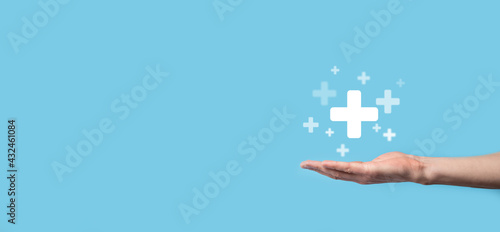 Male hand holding plus icon on blue background. Plus sign virtual means to offer positive thing like benefits, personal development, social network Profit,health insurance, growth concepts photo