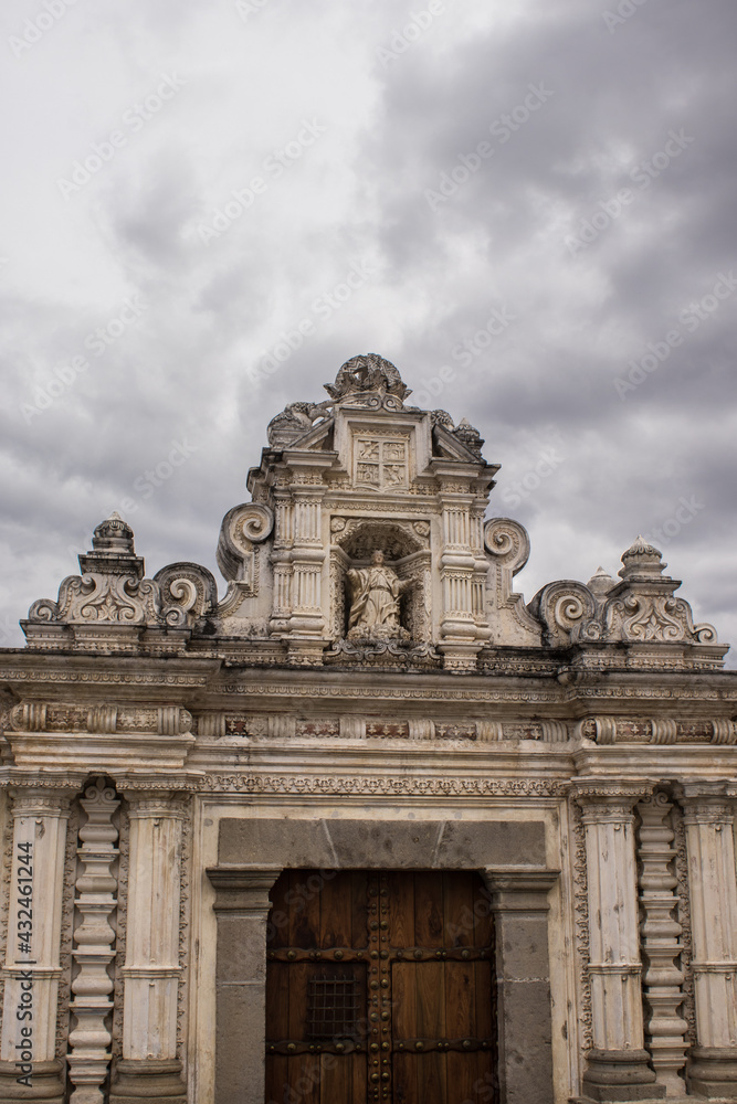 Naklejka premium beautiful classic colonial architecture style building facade with wooden door and dark gray sky