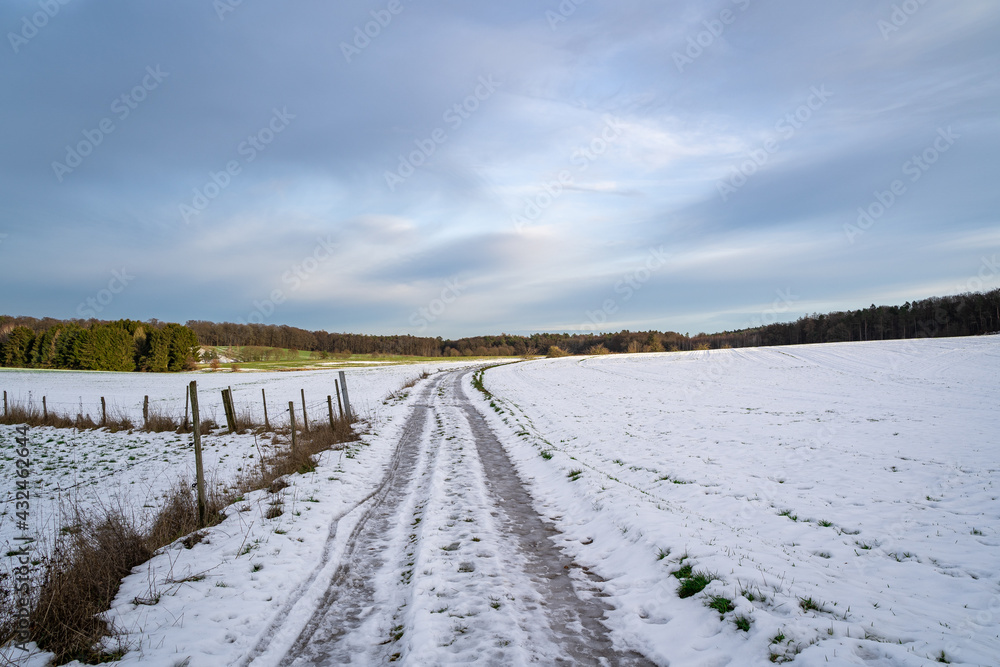 Country road with snow and beautiful blue cloudy sky 