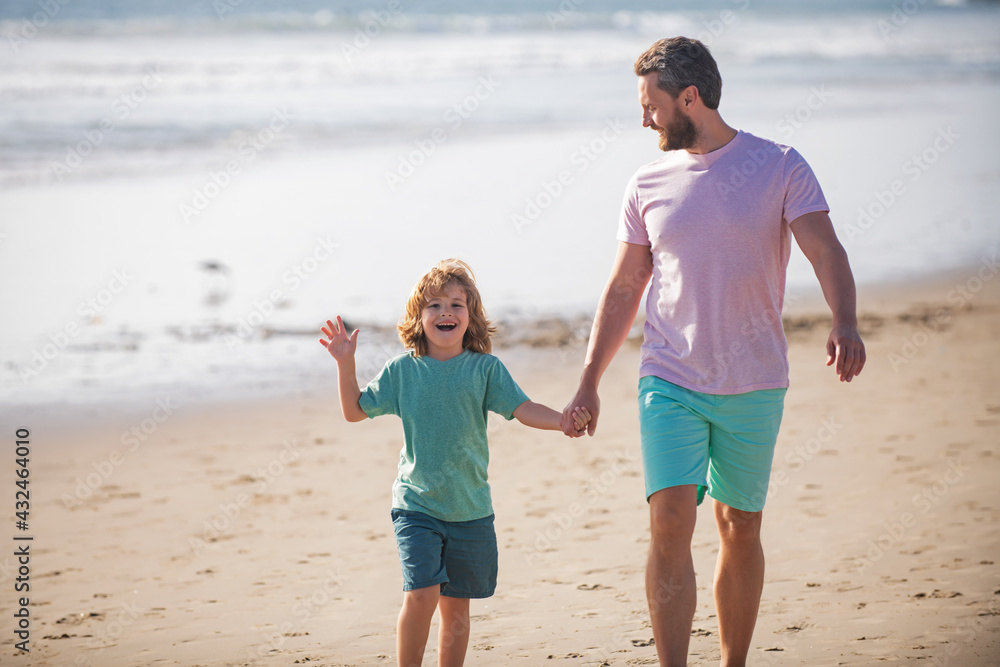 Father and son walking on summer beach. Dad and child boy holding hands and walk together. Family travel, vacation, father's day concept. Father and son walking on summer beach. Dad and child boy holding hands and walk together. Family travel, vacation, father's day concept.