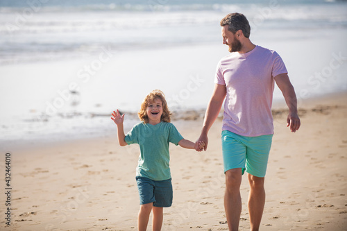 Father and son walking on summer beach. Dad and child boy holding hands and walk together. Family travel, vacation, father's day concept.