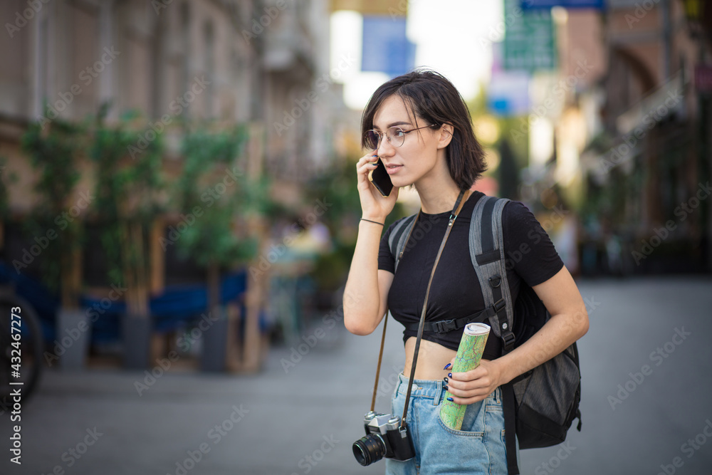 Tourist woman standing on street and talking on phone.