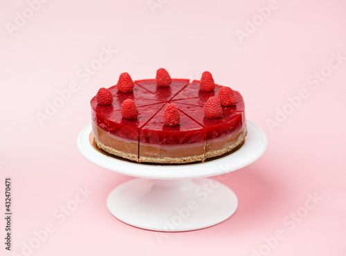 On a pink background, a white cake stand. Healthy Raspberry Layer Cake sugar-free and gluten-free for the diet. On a pink background, a white cake stand.  Space for the text.