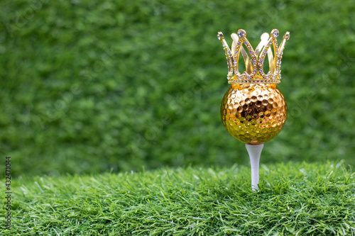 Golden golf ball is on green grass background