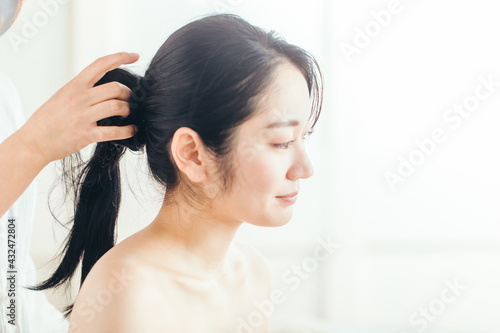 ヘアメイク・髪の毛を縛る女性 