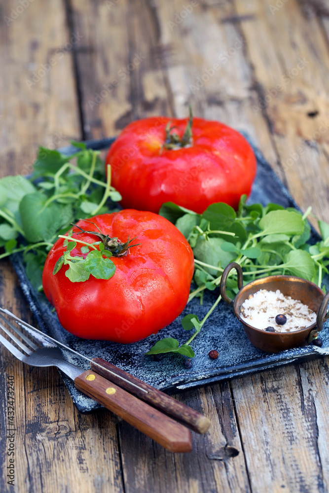 grandes tomates vermelhos maduros com salada de agrião e sal do mar estão em uma bandeja - uma excelente opção para uma dieta saudável. grandes tomates vermelhos maduros com salada de agrião e sal do mar estão em uma bandeja - uma excelente opção para uma dieta saudável.