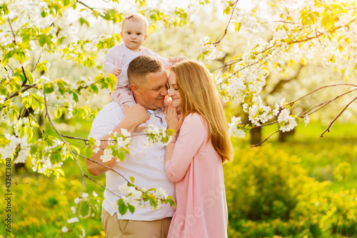 family with a baby daughter in spring flowering garden. cleft lip in infants. photo