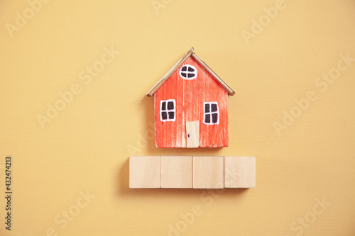 Wooden house model and cubes on yellow background.