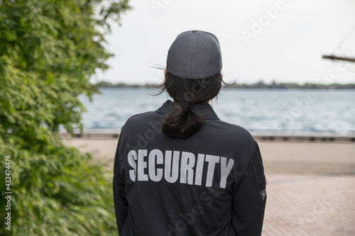 Female security guard in uniform and mask watching over harbor area