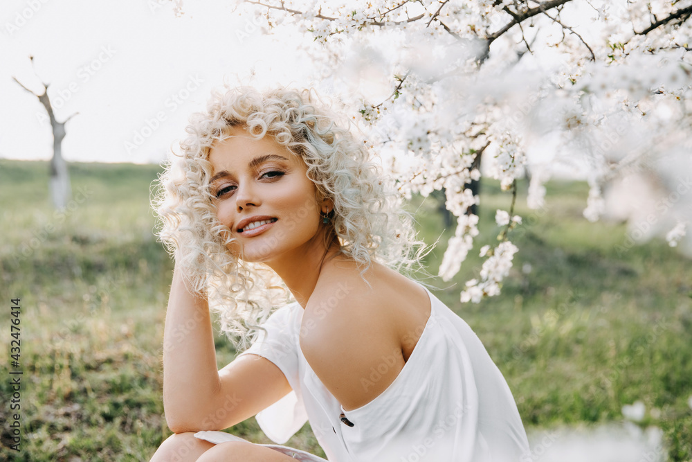 Beautiful young blonde woman with curly hair, wearing a white dress ...