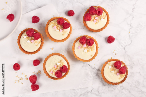 Fotografi Homemade small tartlet pastries with white cream, topped with raspberry fruits a