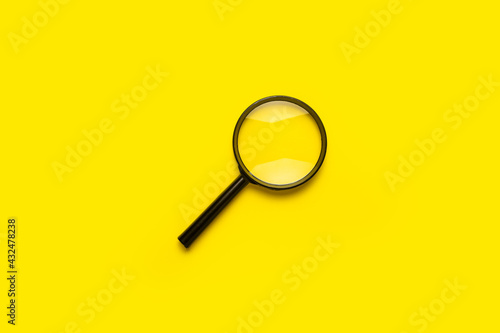 magnifying glass loupe search symbol on yellow background with copy space.