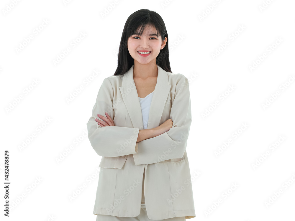 A portrait of happy young asian business woman wearing an ivory colored suit standing with confident and crossed arms on white background