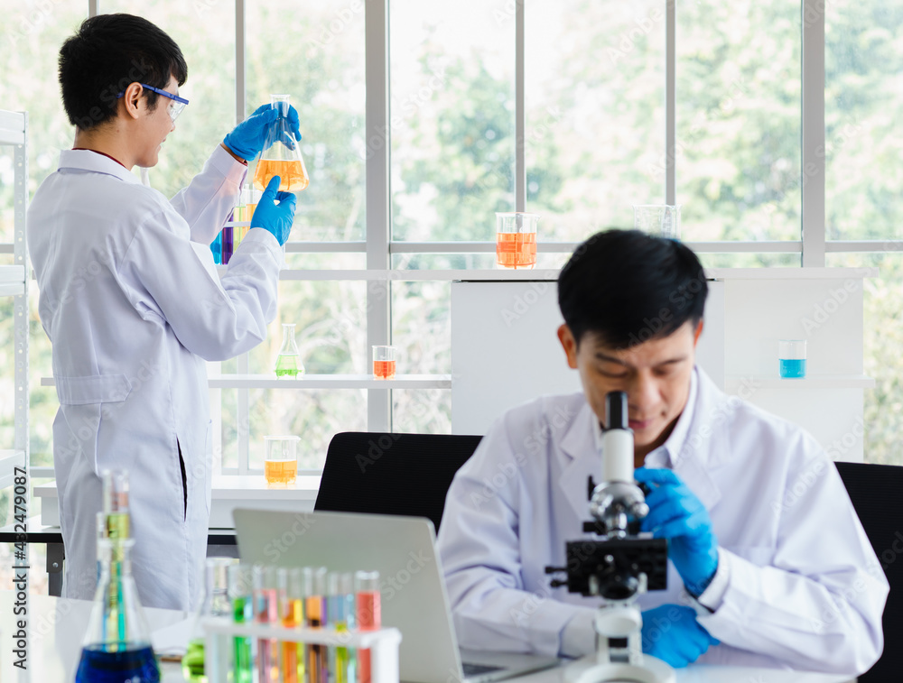 2 asian male scientist working with sample test tube with chemical liquid together in laboratory room. 2 asian male scientist working with sample test tube with chemical liquid together in laboratory room.