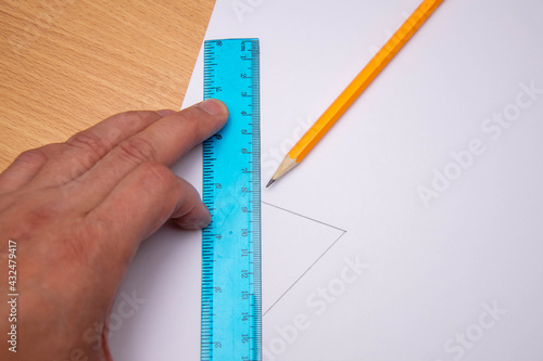 Drawing straight line with pencil and ruler in exercise book