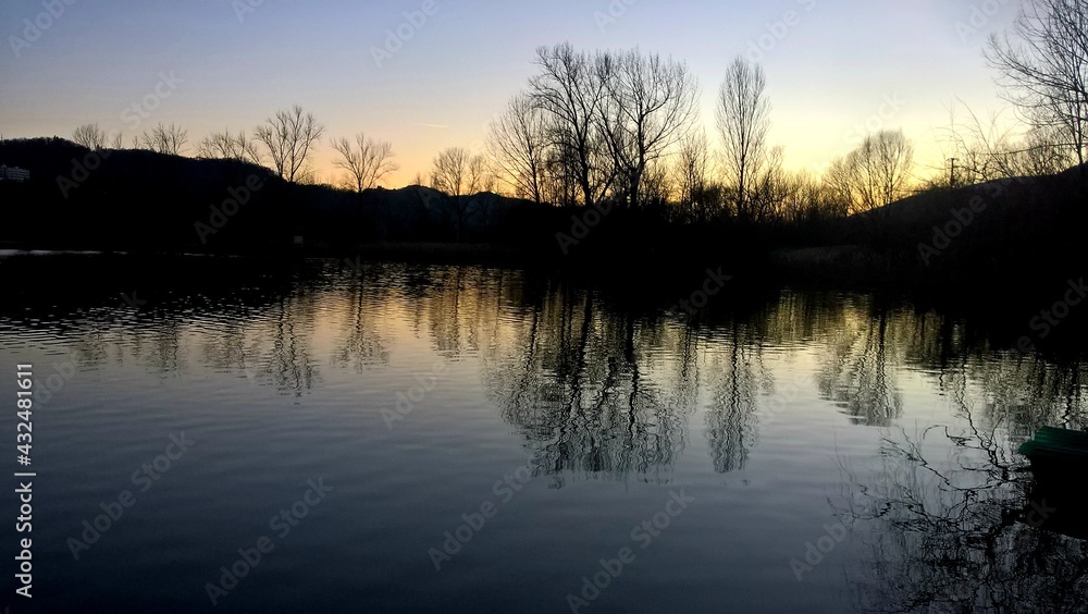 sunset at coast of the lake. Nature landscape. Nature in northern Italy. reflection, blue sky and yellow sunlight. landscape during sunset. sunset at coast of the lake. Nature landscape. Nature in northern Italy. reflection, blue sky and yellow sunlight. landscape during sunset.