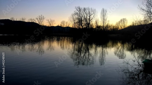 sunset at coast of the lake. Nature landscape. Nature in northern Italy. reflection, blue sky and yellow sunlight. landscape during sunset.