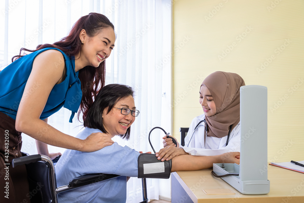 Senior woman patient with relative daughter having consultation with doctor in office clinic hospital, measure blood pressure with sphygmomanometer, looking at camera Senior woman patient with relative daughter having consultation with doctor in office clinic hospital, measure blood pressure with sphygmomanometer, looking at camera