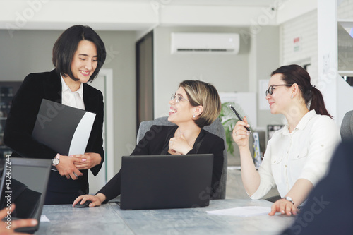 Three young successful business women in the office, together, happily working on a project