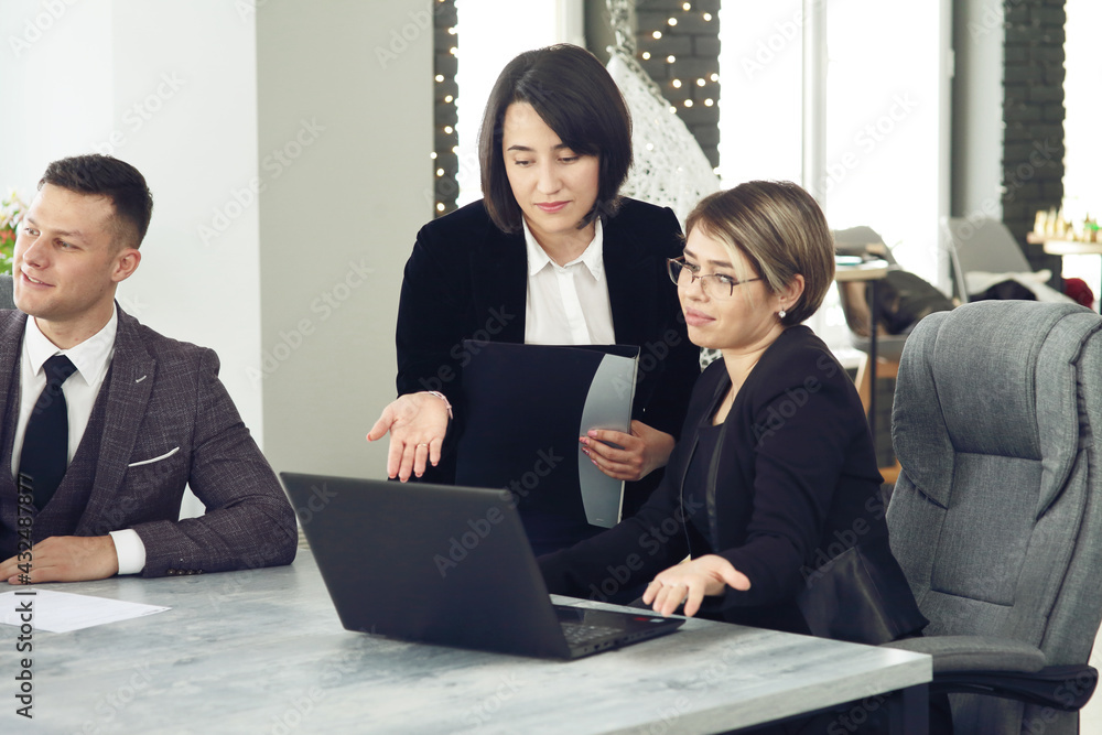 Two young business women in the office, analyzing information looking into a laptop Two young business women in the office, analyzing information looking into a laptop