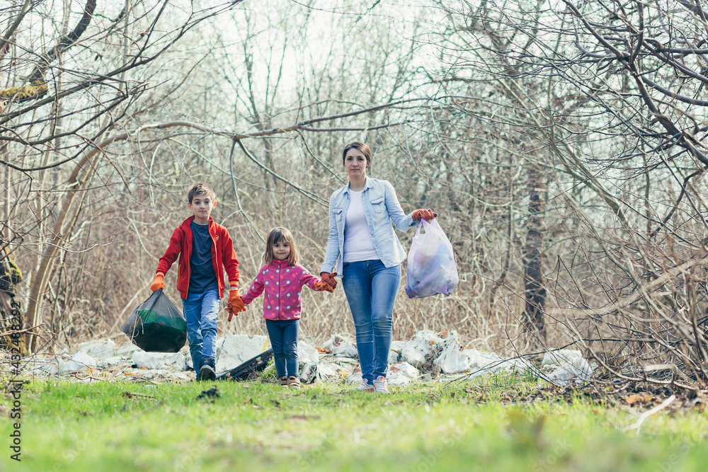 Young family mother with two children volunteers clean the spring park, collect garbage and plastic bottles, spend time together, learn to take care of the environment and take care of it