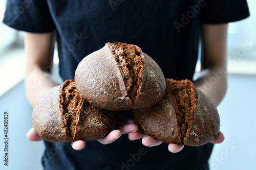 Rye homemade bread on sourdough, three loaves in the hands of a baker