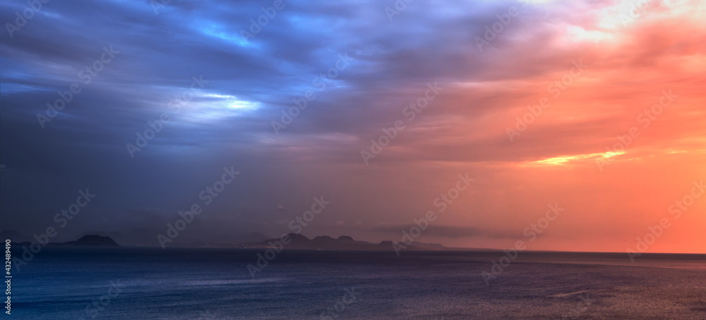 mountains on the horizon with foreground sea and cloudy sky