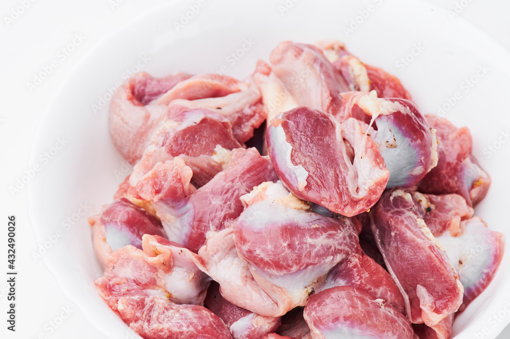Raw chicken thighs on a white plate on a white background. Photo for clipping. Mockup