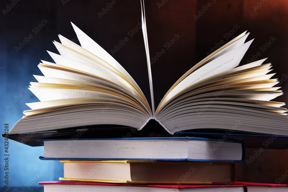 Fototapeta premium A composition with an open book lying on a stack of other books