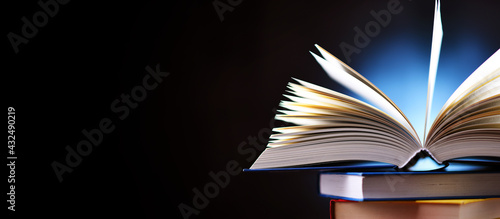 A composition with an open book lying on a stack of other books photo